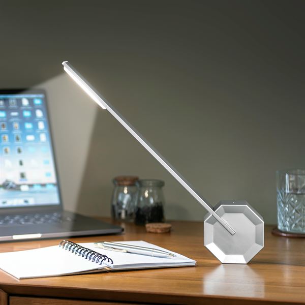 Gingko Octagon one desk lamp in Silver Aluminium lightng up a book