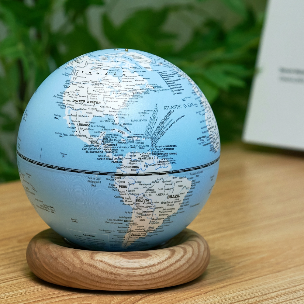 Gingko Mini Light Blue Atlas Globe with White Ash Base unlit on a desk